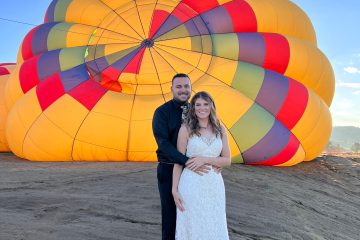 married couple posing for the camera in front of pagosa adventure's hot air balloon in pagosa springs, colorado