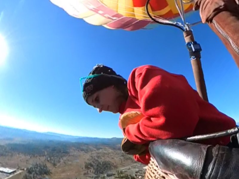 a woman looking down at the scenery on board pagosa adventure's hot air balloon in pagosa springs, colorado