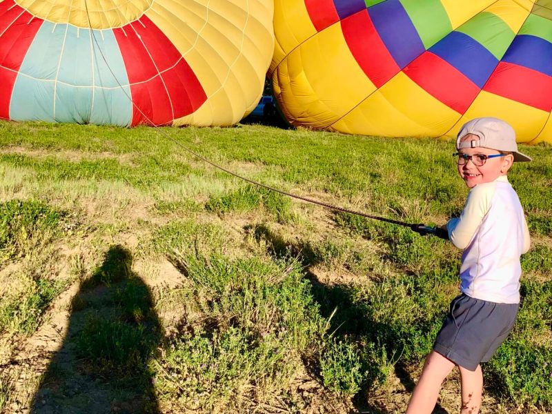 a little boy posing for the camera in front of pagosa adventure's hot air balloon in pagosa springs, colorado