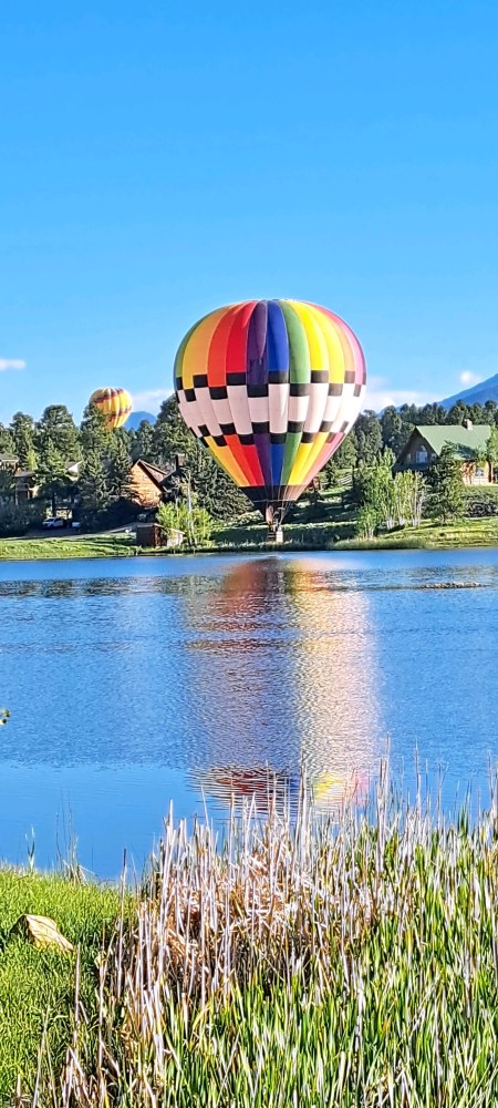 a hot air balloon flying over a body of water