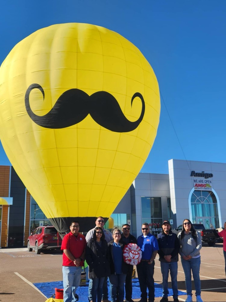 a group of people standing in front of a large balloon in the sky