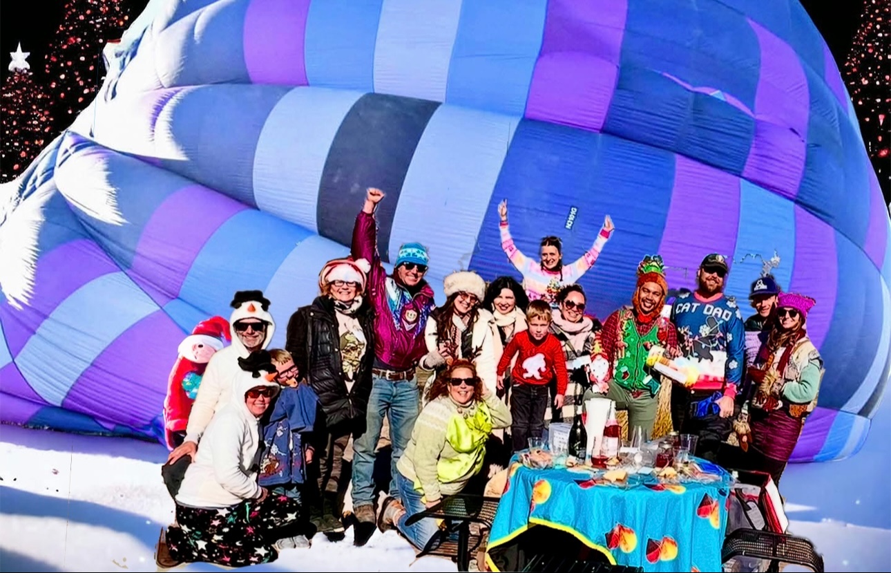 Ugly Sweater Contest a group of people posing for the camera in front of a hot air balloon