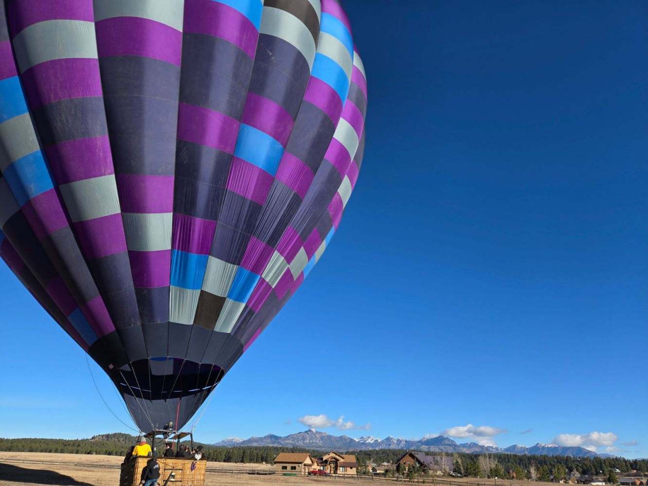 A large purple hot air balloon on the ground waiting for passengers to embark